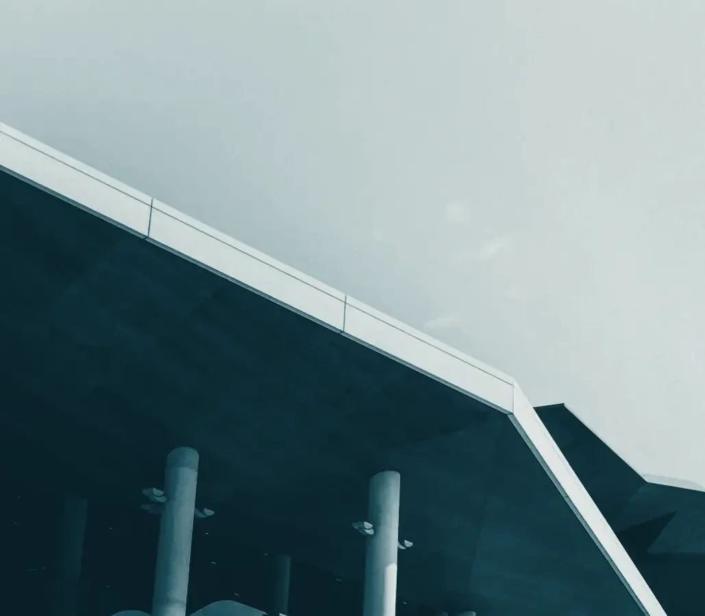 The angular roof and columns of a modern building against the sky