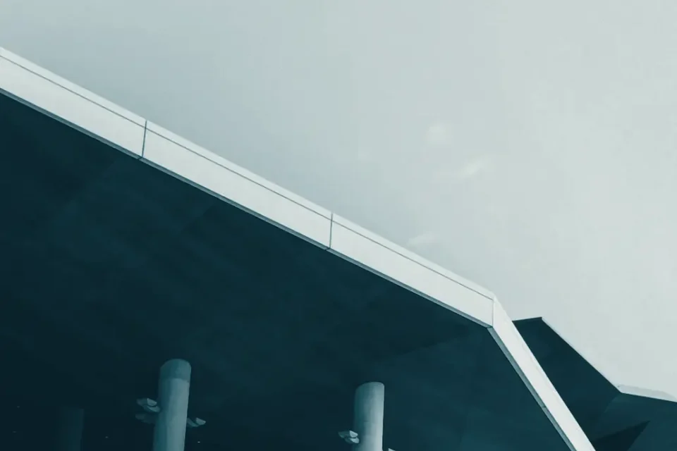 The angular roof and columns of a modern building against the sky
