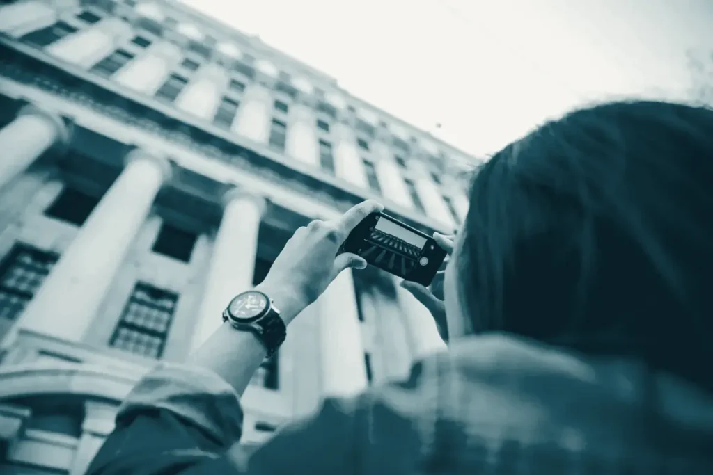 A person photographing a classical building with columns