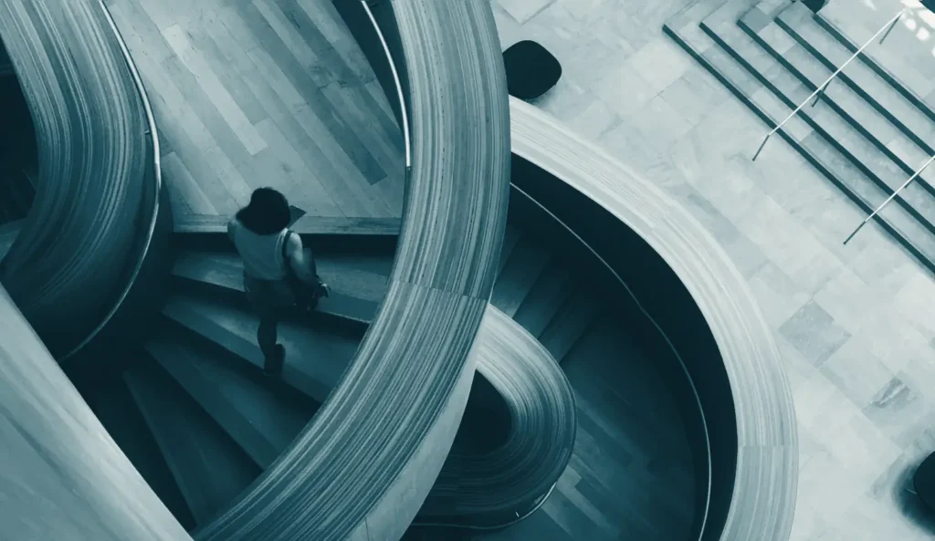 A person climbing a spiral staircase, seen from above