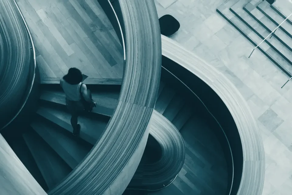 A person climbing a spiral staircase, seen from above